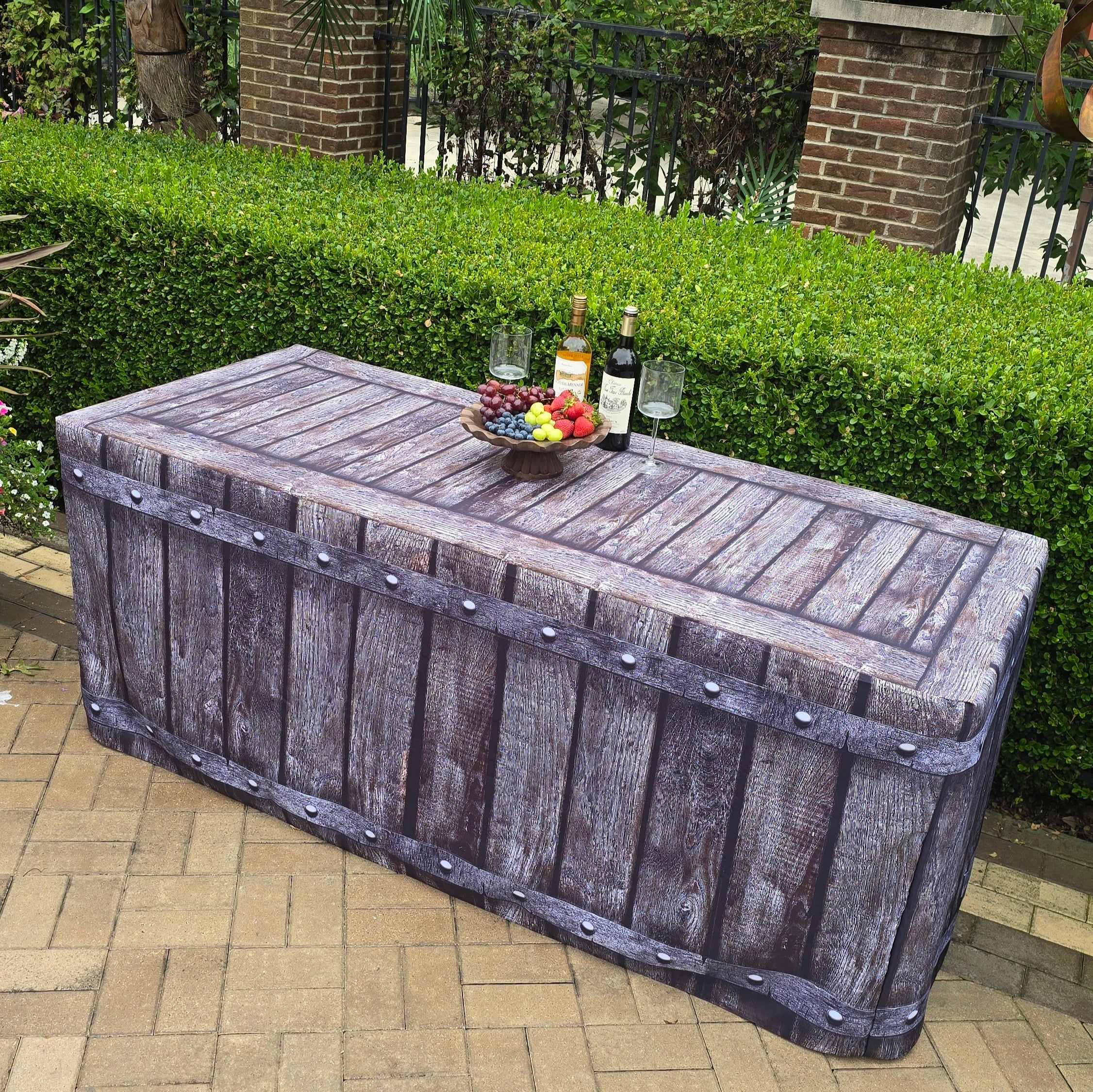 A 6ft folding table with a fabric fitted table cover that looks like wood with rivets. Used outside by a pool during a special event with charcuterie and wine.