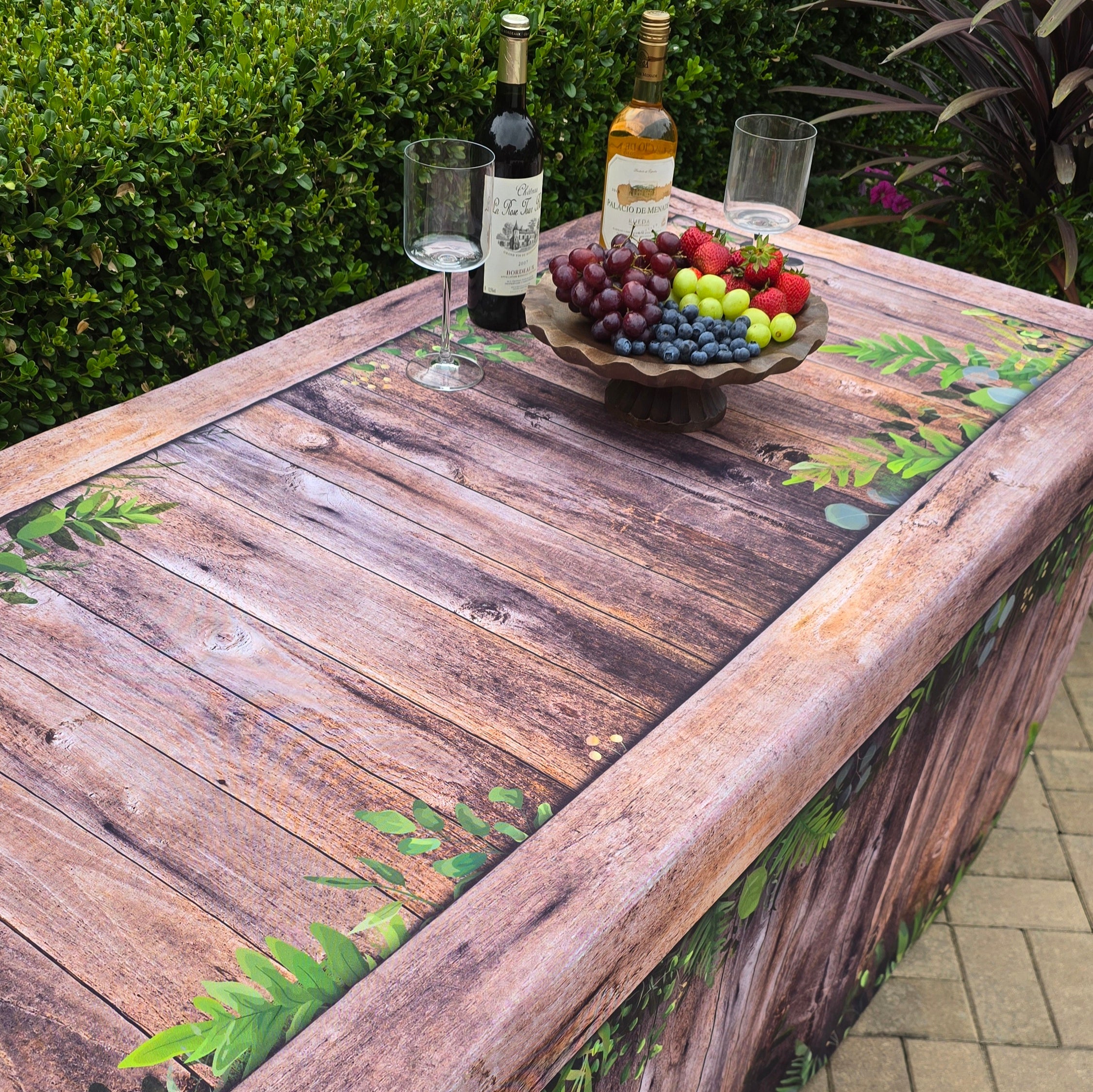 Fabric fitted table cover with a botanical rustic oak faux wood look design for folding tables at events.