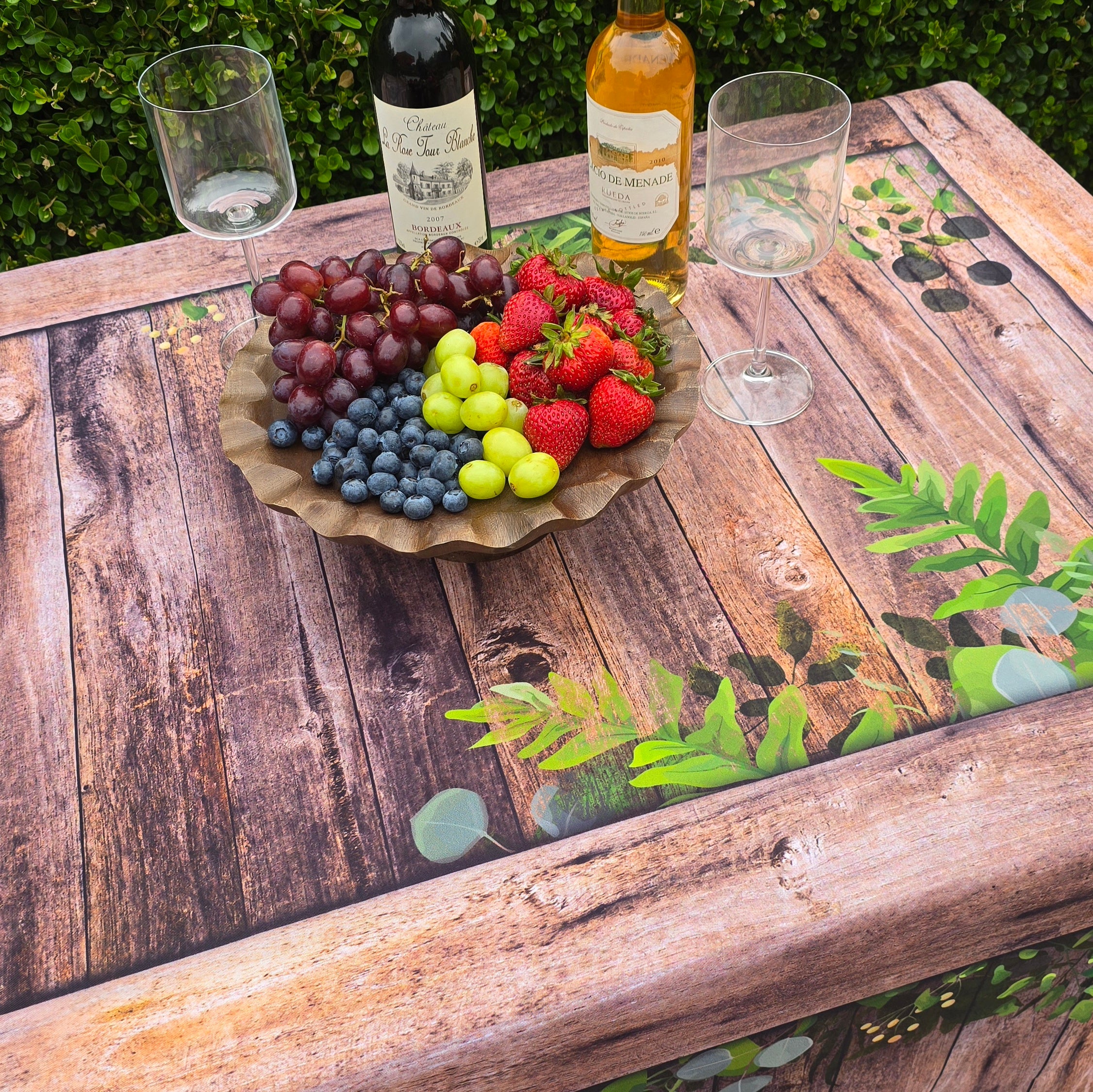 A rustic looking fitted fabric table cover that looks like real wood with a botanical design for special events.