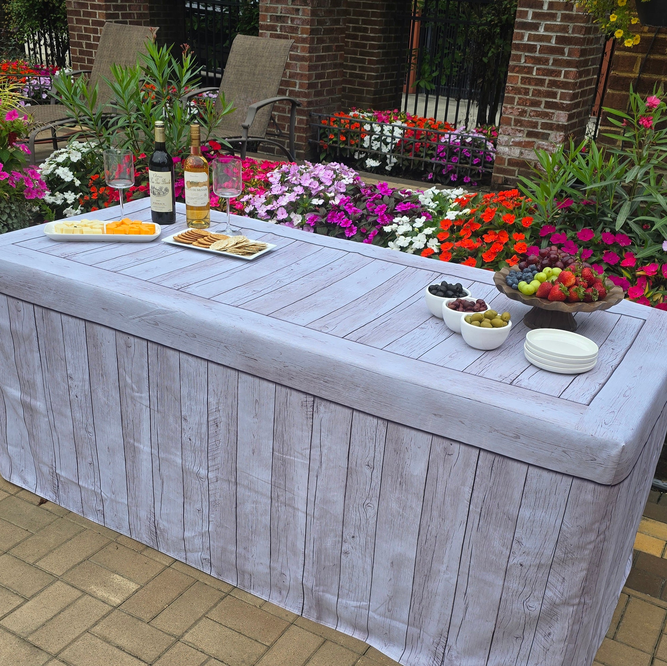 6FT table cover with a faux wood look table cover at an outdoor event with charcuterie and catered food.