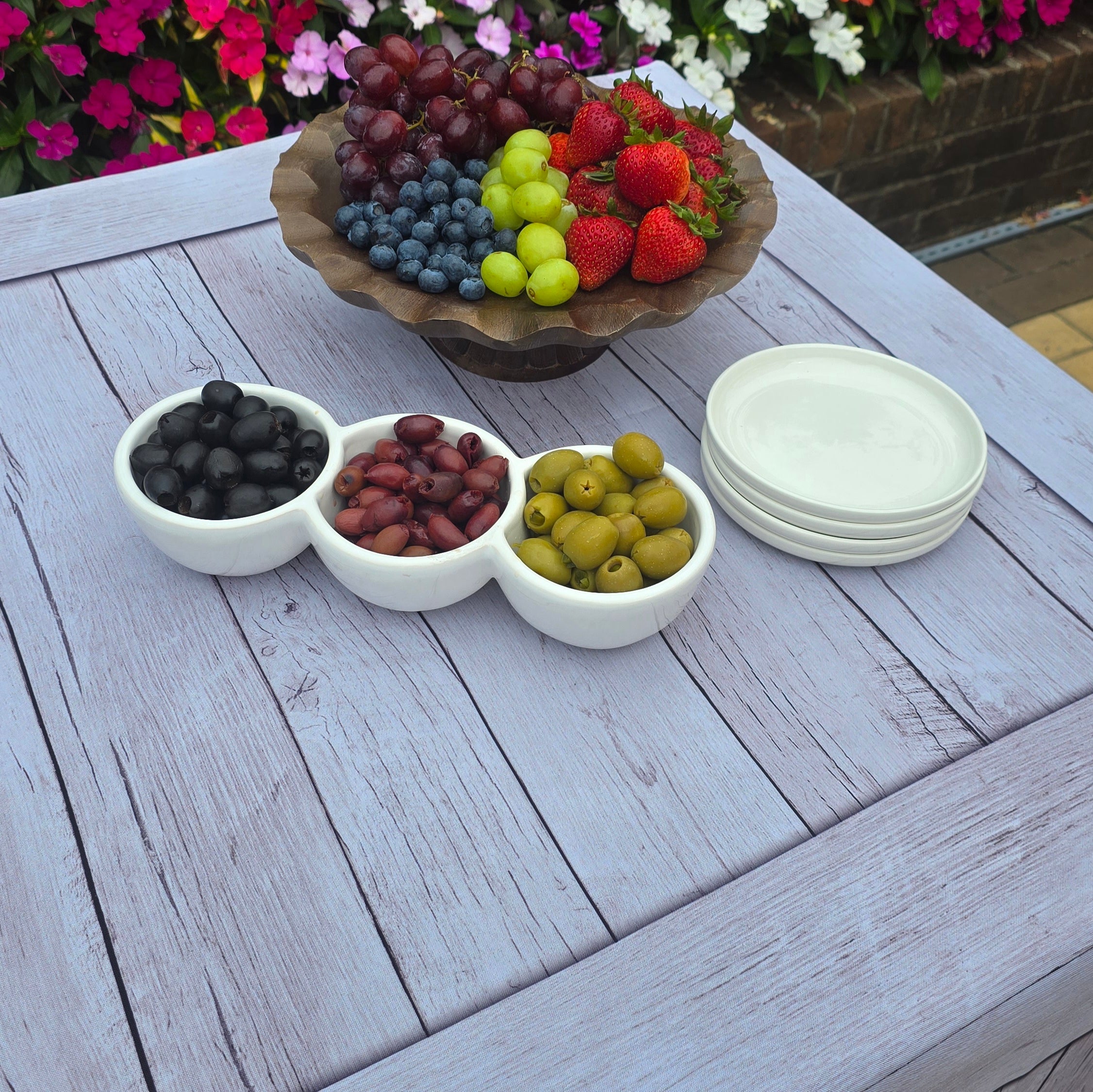Close up picture of a folding table covered with a wood grain fabric table cover with appetizers on top.